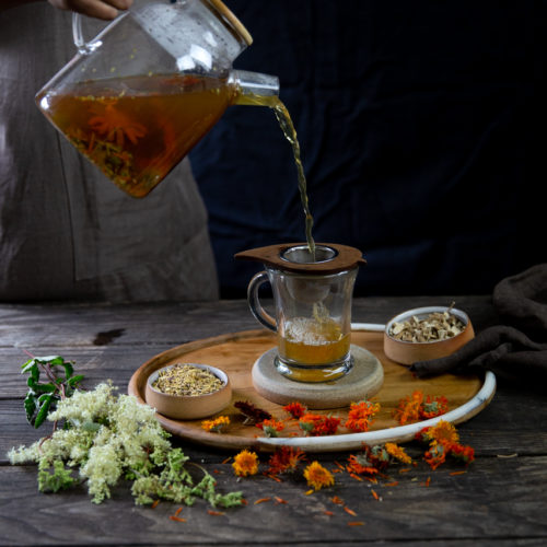 A person pours a cup of calendula tea.