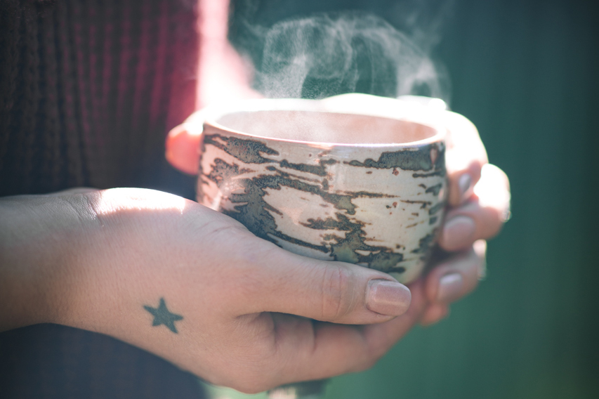 Someone holds a cup of steaming tea.