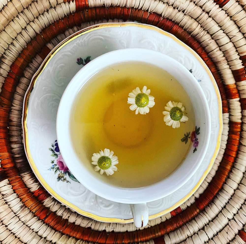 A full teacup of Balm in Gilead Tea with floating flowers.